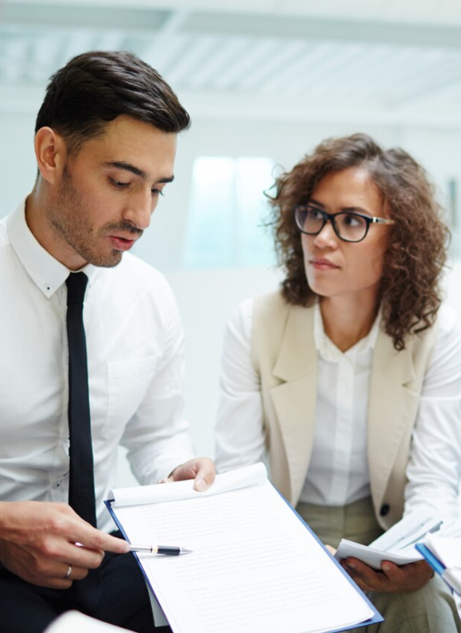 Deux consultants en réunion analysant un document de projet stratégique.