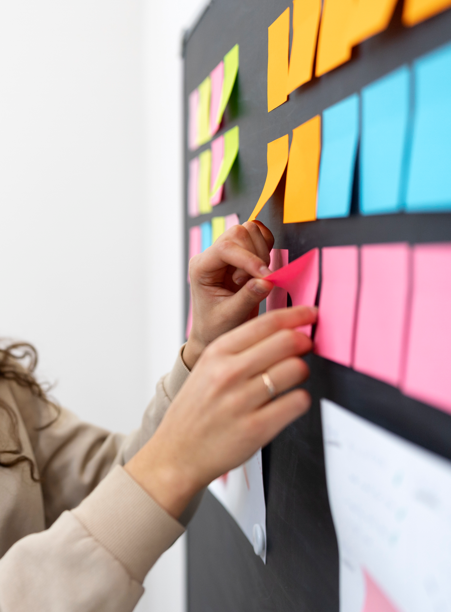 Project Management Officer organisant un tableau de tâches avec des post-it pour le suivi de projet.