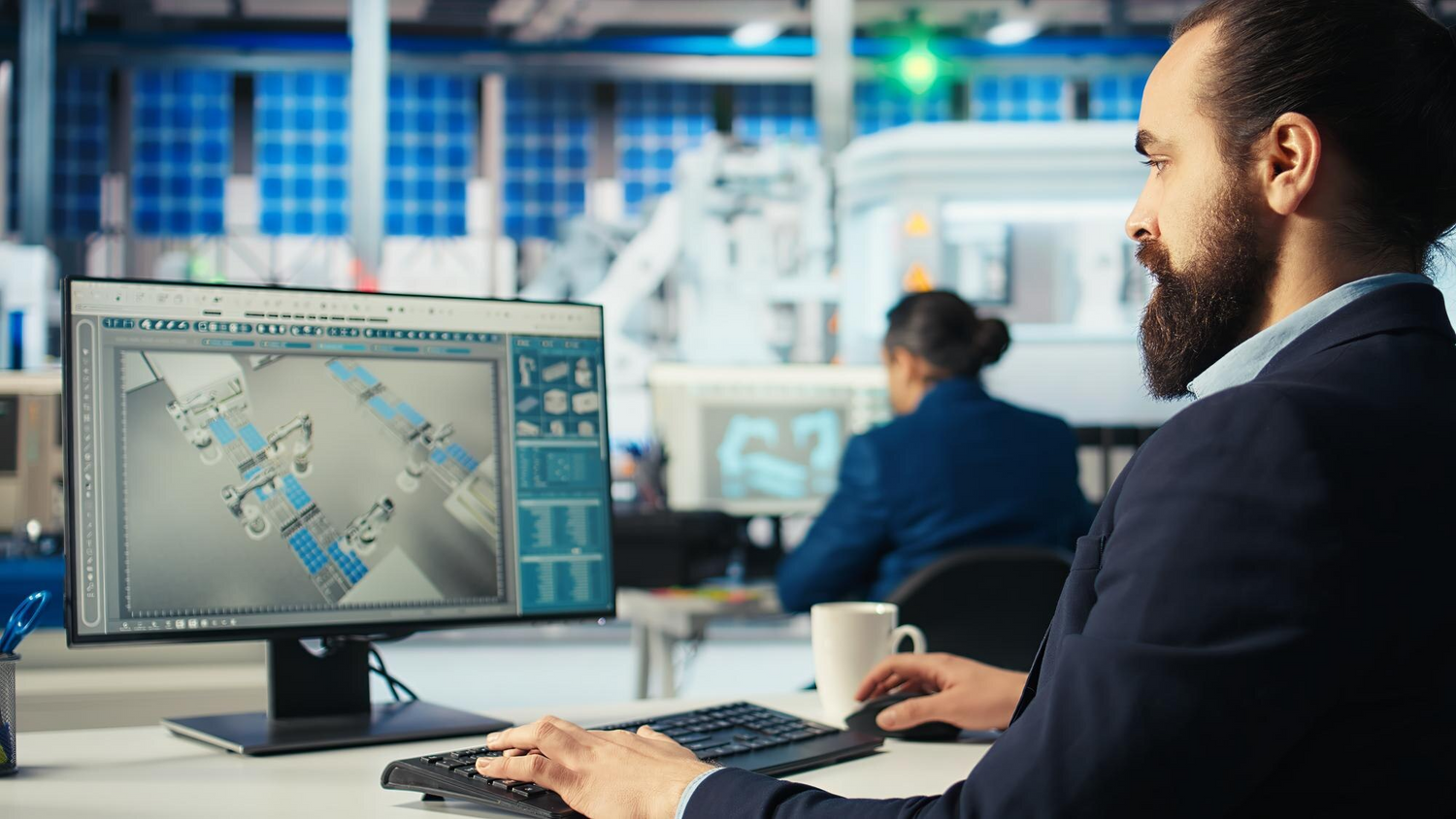 Ingénieur en bureau d’études utilisant un logiciel de modélisation 3D pour concevoir une ligne de production automatisée avec robots industriels.