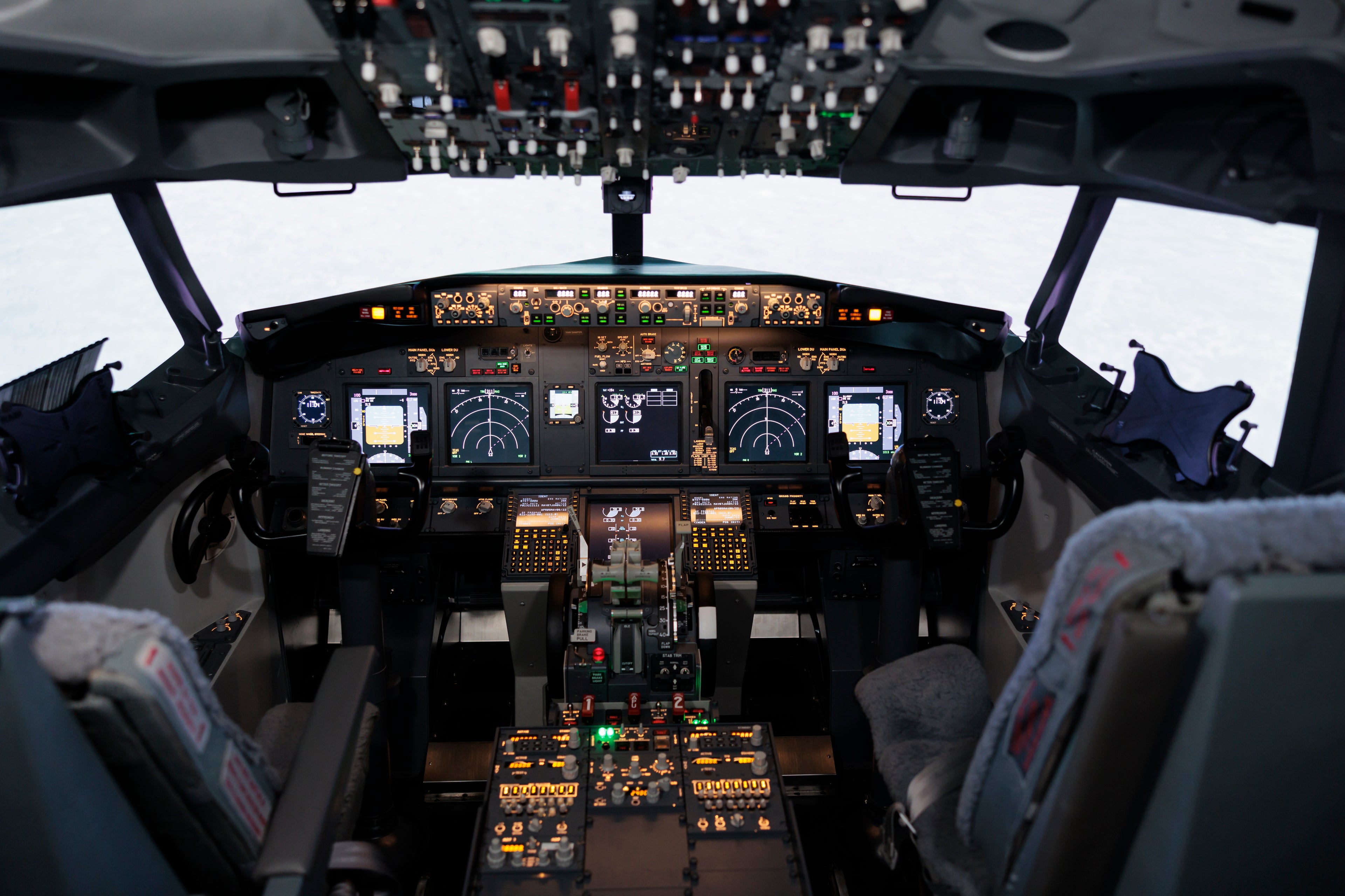 Vue intérieure d’un cockpit d’avion moderne avec instruments de vol numériques et commandes de pilotage, représentant le secteur aéronautique et aérospatial.