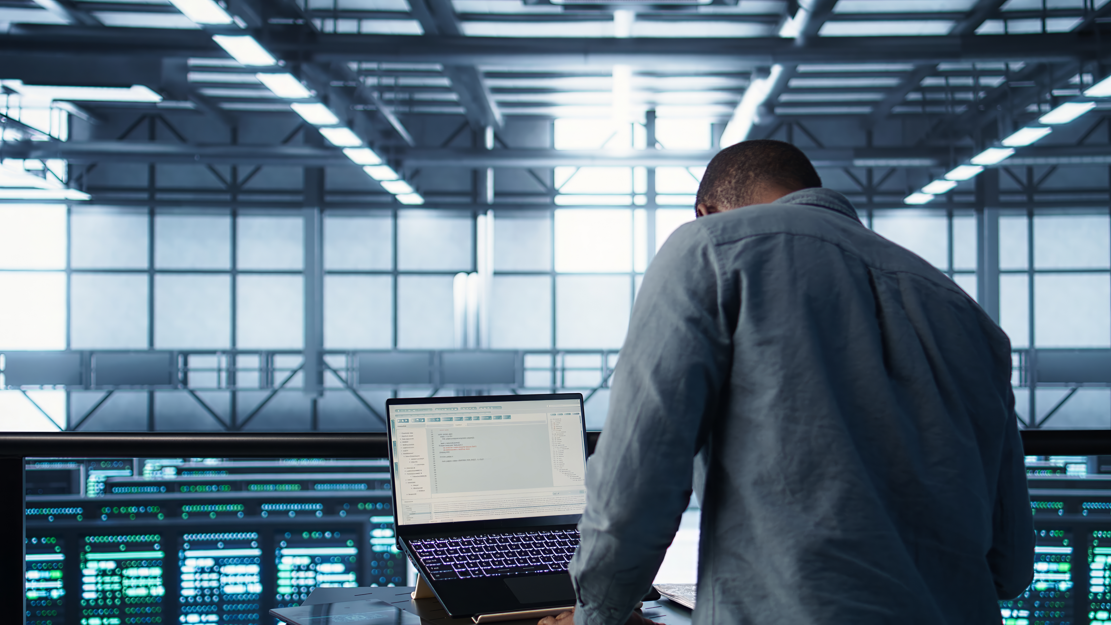Ingénieur en cybersécurité travaillant sur un ordinateur portable dans un centre de données, surveillant et analysant des systèmes informatiques.